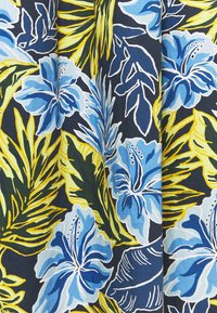 Fleurs d'hibiscus bleues et feuilles tropicales vertes et jaunes sur un tissu à fond sombre avec un motif floral éclatant.