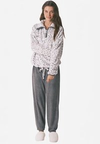 Fleece pullover with a half-zip collar in white featuring a pastel pattern, paired with gray jogger pants and white fluffy slippers.