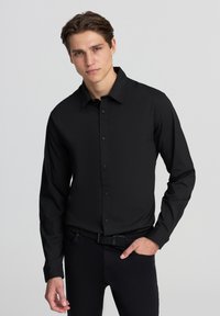 Czarna, długim rękawem, zapinana koszula z usztywnionym ko�łnierzykiem, wykonana z gładkiego materiału. Posiada regularny krój i subtelną teksturę.