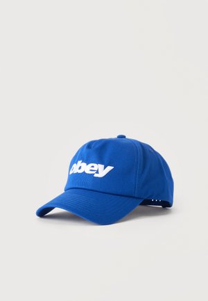 Kék, állítható baseball sapka fehér "obey" hímzett felirattal az elején, egyszínű világos háttér előtt.