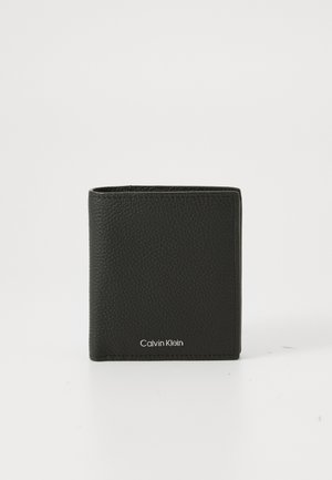 Black textured leather bi-fold wallet with silver Calvin Klein logo on front, standing upright on white background.