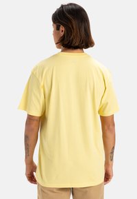 Camiseta de algodón amarilla de manga corta, con cuello redondo y corte relajado. Textura suave, sin patrones ni gráficos visibles.