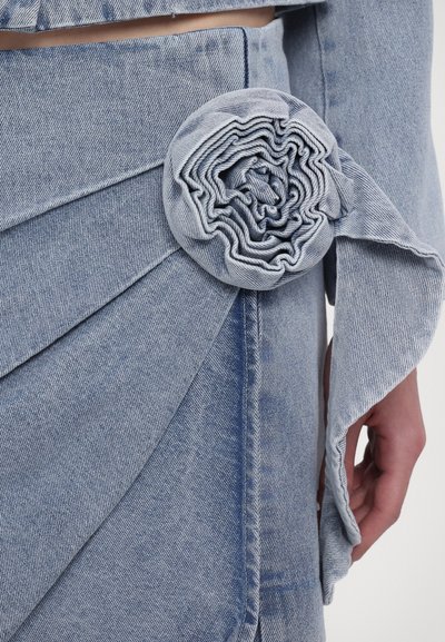 Hellblauer Denimrock mit einem strukturierten Blumendetail an der Taille, mit schichtiger Stoffgestaltung und einem weichen, zerknitterten Aussehen.