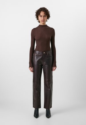 Brown ribbed knit sweater with high neck and long sleeves, paired with dark brown leather straight-leg pants featuring gold hardware accents.