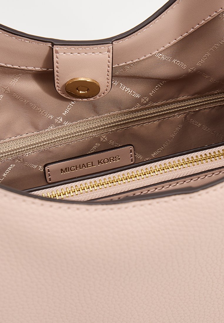 Lichtroze lederen handtassenv interior met een gouden drukknoopsluiting, geperst logo en een ritsvak met gouden ritssluiting.