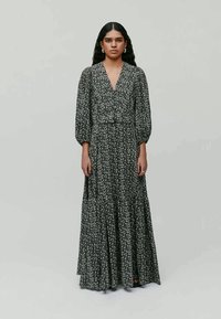 Maxikleid in Schwarz mit weißem Blumenmuster, V-Ausschnitt und Puffärmeln. Fließender Rock mit gerafftem Bund und subtiler Textur.
