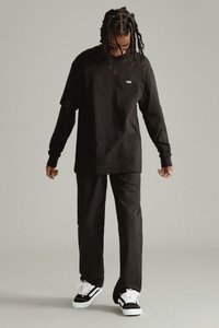 Camiseta de algodón negra y pantalones de corte relajado. Presenta un pequeño logo blanco en el pecho. Combinados con zapatillas en blanco y negro.
