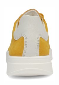 Yellow suede sneaker with white leather heel overlay and thick white rubber sole, viewed from the back.
