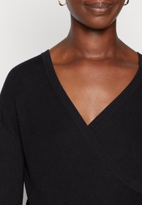 Schwarzes geripptes Wickeloberteil mit tiefem V-Ausschnitt und Raglanärmeln, ausgestattet mit einer glatten Textur und tailliertem Design.