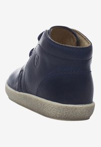 Zapato de cuero azul marino con punta redondeada, suela texturizada y detalle de botón lateral. Presenta un acabado suave y suela de goma de color claro.