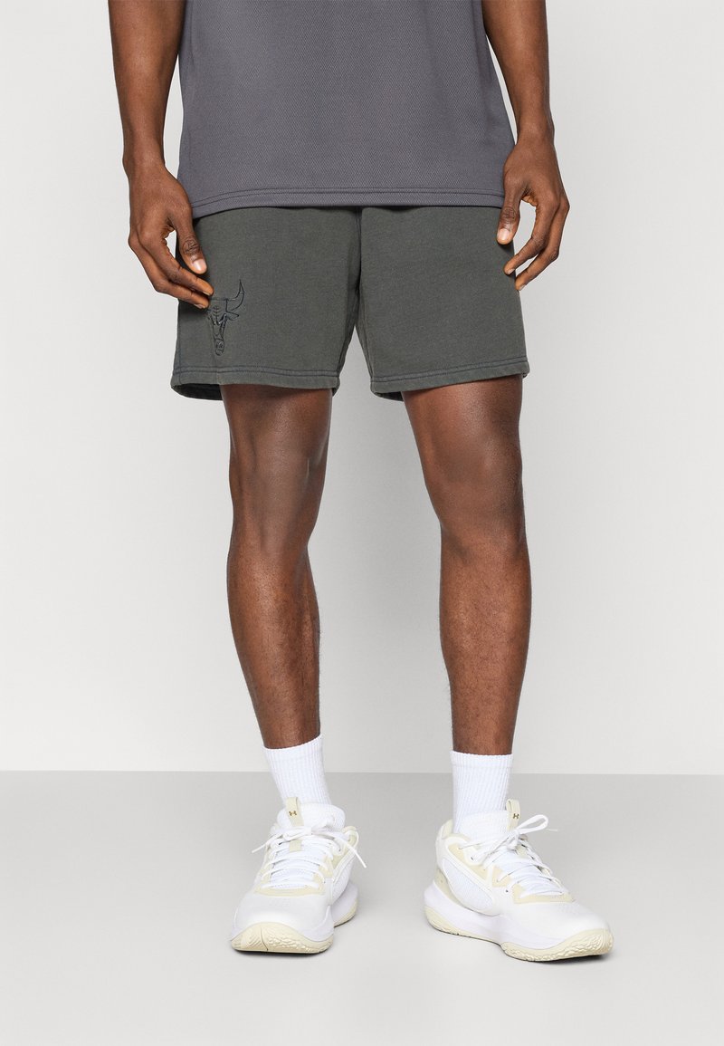 Pantalones cortos de algodón gris con un logo de toro bordado, combinados con zapatillas deportivas blancas y calcetas, con un ajuste relajado y una textura suave.