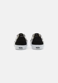 Crne i siva suknjačice s bijelim gumiranim potplatima. Sadrže Vans logo na peti i kontrastne boje akcenta.