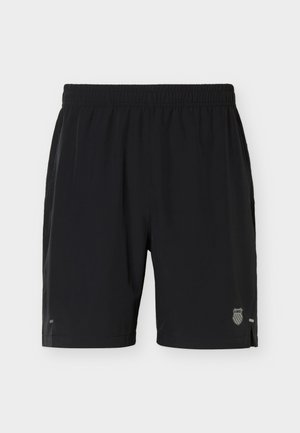 Fekete sportnadrág elasztikus derékpánttal, kis oldalsó hasítékokkal és fényvisszaverő logóval az alsó jobb lábszáron, világos háttér előtt.