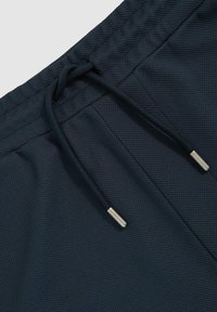 Marineblaue Shorts aus strukturiertem Stoff. Mit einem elastischen Bund und Kordelzügen sowie metallischen Enden. Nähte sind sichtbar.