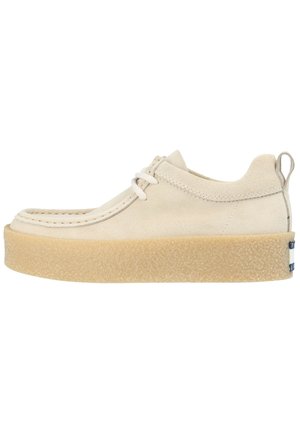Scarpa casual in suede beige con suola in gomma spessa e texture, lacci, dettagli nella cucitura e linguetta sul tallone, mostrata in profilo laterale.
