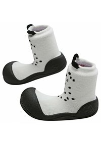 Botines de tela blanca con suelas de goma negra, que presentan una textura estampada, un puño acanalado en el tobillo y dos asas negras para facilitar el calzado.