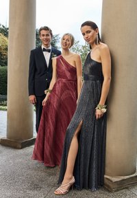 Tres modelos exhiben atuendos formales: un traje negro ajustado, un vestido rojo de un solo hombro y un vestido negro halter con una abertura lateral y un brillo metálico.