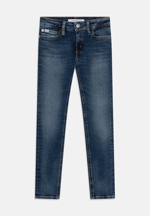 Jean droit en denim bleu foncé avec fermeture par bouton et zip, poches devant et derrière, et étiquette Calvin Klein Jeans à l’intérieur de la ceinture.