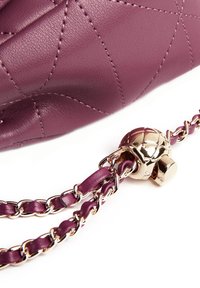 Borsa a tracolla in pelle trapuntata viola con accessori dorati, dotata di una tracolla a catena e un clasp decorativo. Texture liscia con dettagli a pattern cucito.
