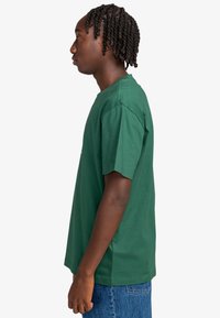Grøn bomulds t-shirt med korte ærmer og rund hals, der har en afslappet pasform og blød tekstur. Ingen synlige mønstre eller accenter.
