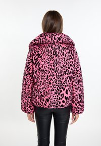 Giacca puffer con stampa leopardata rosa, colletto alto, maniche lunghe e una texture morbida. Presenta macchie leopardate nere e grandi tasche frontali.