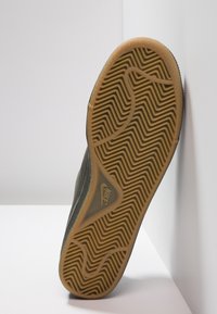 Sole tenisky Nike, gumový materiál, texturovaný vlnitými vzory, převážně hnědý s tmavými akcenty, navržený pro trakci a stabilitu.