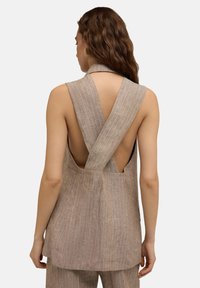 Beige Leinenoberteil mit tiefem V-Ausschnitt hinten und gekreuzten Trägern. Es zeichnet sich durch ein strukturiertes, gestreiftes Muster aus und bietet ein lockeres, leichtes Design.