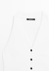 Bílý bezrukávový svetr s V-výstřihem a třemi černými knoflíky, s etiketou Massimo Dutti na výstřihu.