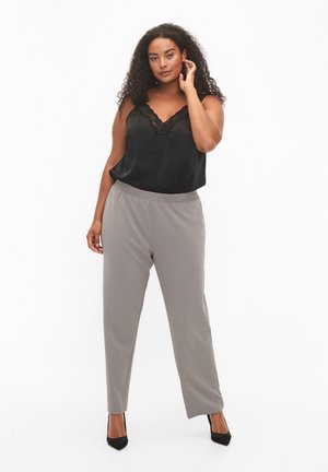 Čierny saténový tielkový top s čipkovým lemom v kombinácii so svetlosivými na mieru ušitými nohavicami. Oblečenie je doplnené čiernymi vysokými podpätkami.