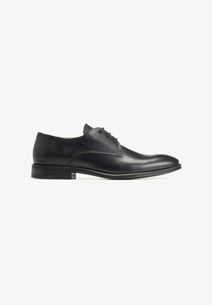 Chaussure habillée en cuir noir avec une surface lisse, bout arrondi et talon bas empilé. Elle présente un laçage et de minimalistes accents de couture.