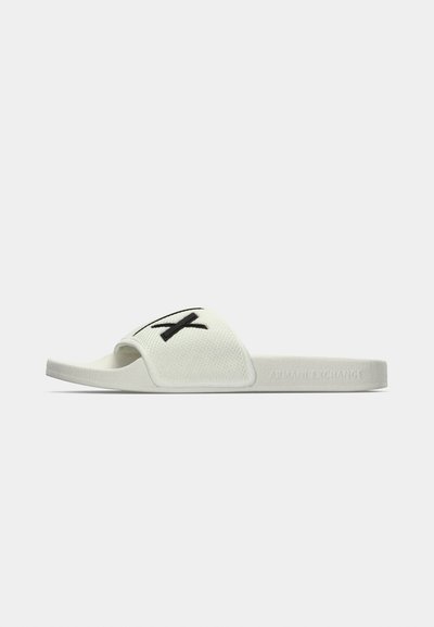 Sandale blanche à glissière avec dessus en tissu texturé, détail logo noir et semelle en caoutchouc rembourrée. Design minimaliste avec bout ouvert.