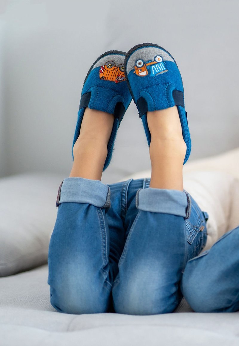 Blaue Filzschlappen mit grauen Akzenten, verziert mit bunten Fahrzeugmotiven auf den Zehen, kombiniert mit hochgekrempelten Jeanshosen.