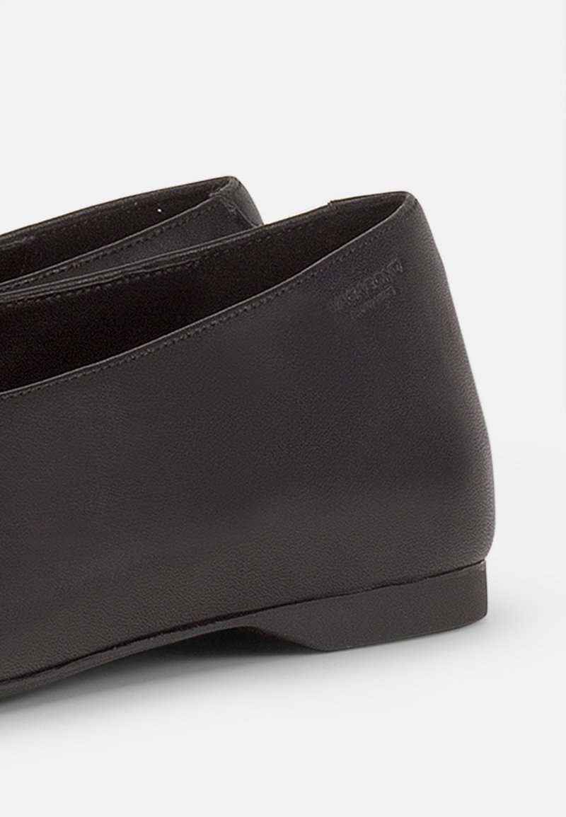Scarpa in pelle nera con tacco basso, forma arrotondata, texture liscia e design minimale. Logo discreto impressa di lato.