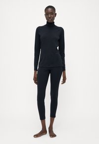 Ensemble en col roulé noir à manches longues et leggings, fabriqué dans un tissu doux, avec un design ajusté et des détails de couture minimalistes.