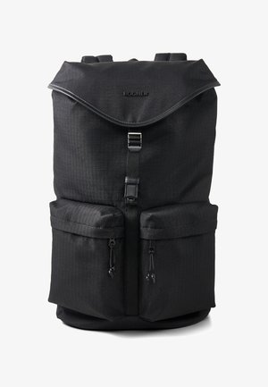 Czarny plecak o teksturowanej powierzchni, z dwoma przednimi kieszeniami, regulowanymi paskami oraz klapą na górze zapinaną na klamrę. Widoczne logo marki.