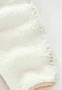 Tessuto in pile bianco e morbido, con una texture soffice, caratterizzato da un nastro color crema con la scritta "BAKER by TED BAKER" in rilievo grigio chiaro.