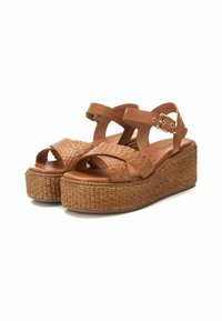 Sandalias de cuña de cuero trenzado marrón con tiras trenzadas y hebilla en el tobillo. Presentan una suela de plataforma de yute texturizado para mayor altura.