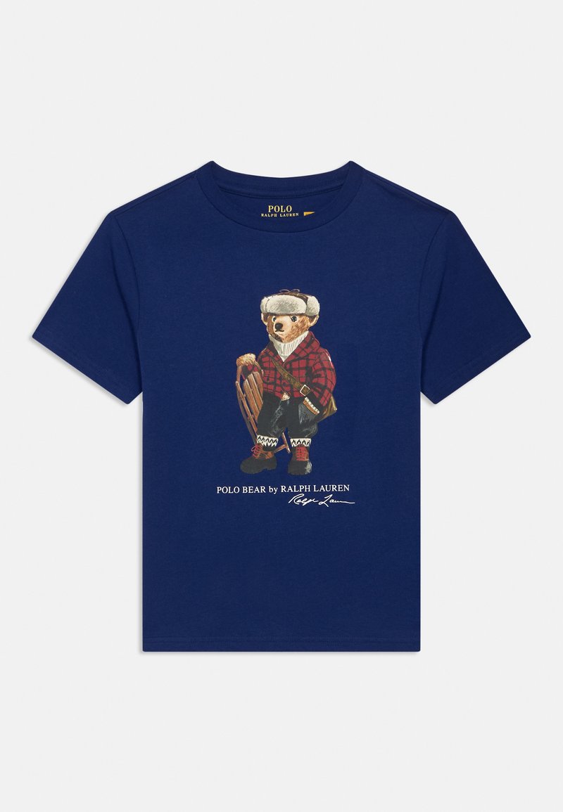 Námornícky bavlnený tričko s ilustráciou medveďa v červenej kockovanej košeli a čiapke, ktorý drží sanice, s textom "Polo Bear od Ralph Lauren" nižšie.