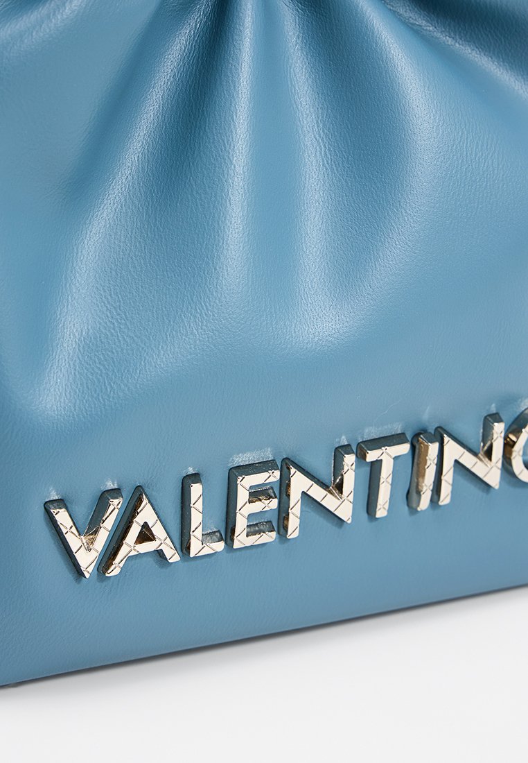 Sac en cuir bleu clair avec texture plissée et lettres métalliques dorées en relief épelant "VALENTINO" à l'avant.