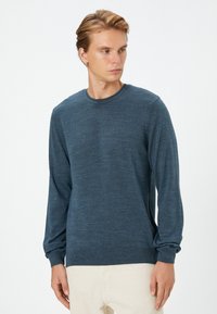 Dunkelblauer Langarmpullover aus strukturiertem Strickstoff, mit einem Rundhalsausschnitt sowie gerippten Bündchen und Saum. Klassische Passform.