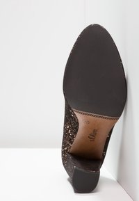 Chaussure à talons hauts noire avec dessus texturé, présentant un motif en bronze brillant. Talon noir solide et semelle en caoutchouc, marqués de la marque et de la taille.