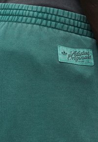 Πράσινο αθλητικό σορτς από απαλό ύφασμα, με ελαστική μέση και λογότυπο "Adidas Originals" σε ραμμένη σχεδίαση.