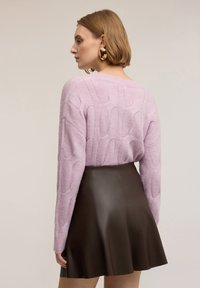 Maglione lavorato a maglia color lilla chiaro con motivo a texture, abbinato a una gonna svasata in pelle marrone. Tessuto morbido e design comodo e rilassato.