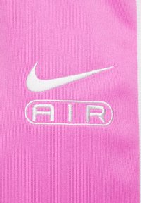 Rozā audums ar baltu Nike Swoosh logotipu un vārdu "AIR" baltā rakstā, radot gludu, teksturētu izskatu.