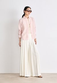 Striped pink and white button-up shirt paired with wide-leg cream trousers. Accessories include oversized sunglasses and simple earrings.