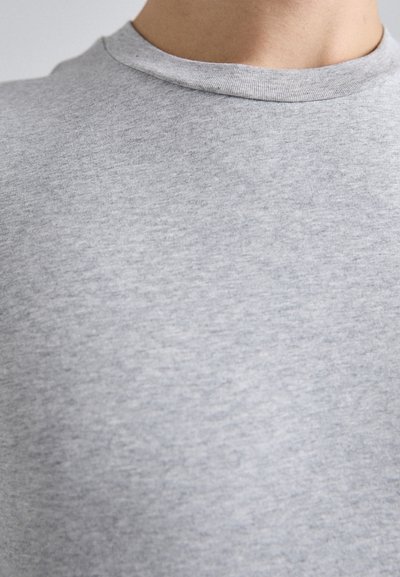 T-shirt gris à col rond en coton doux, avec une texture lisse et un col côtelé, affichant un léger motif chiné.