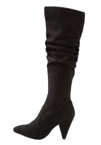 Botas negras hasta la rodilla hechas de suave ante, con un diseño holgado, punta afilada y un tacón cónico de altura media.