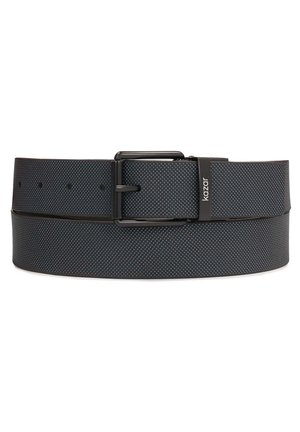 Zwarte gestructureerde leren riem met zwarte metalen gesp en "kazar" logo op de riemlus, plat opgerold tegen een witte achtergrond.