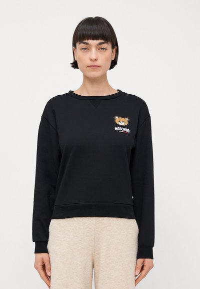Czarny sweatshirt z okrągłym dekoltem, ściągaczami przy rękawach i u dołu; zdobiony nadrukiem niedźwiedzia oraz logo "Moschino" na klatce piersiowej.