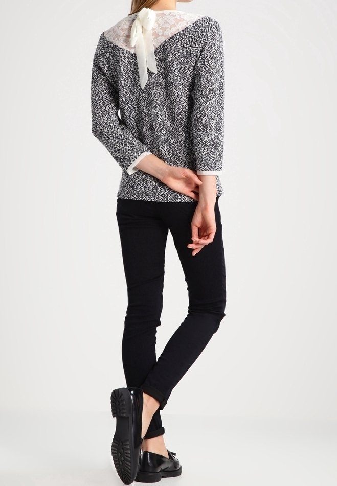 Svart och vitt mönstrad topp med spetsbak och snörning, tillsammans med svarta skinny jeans och svarta platta skor. Anmärkningsvärt texturerad tyg.